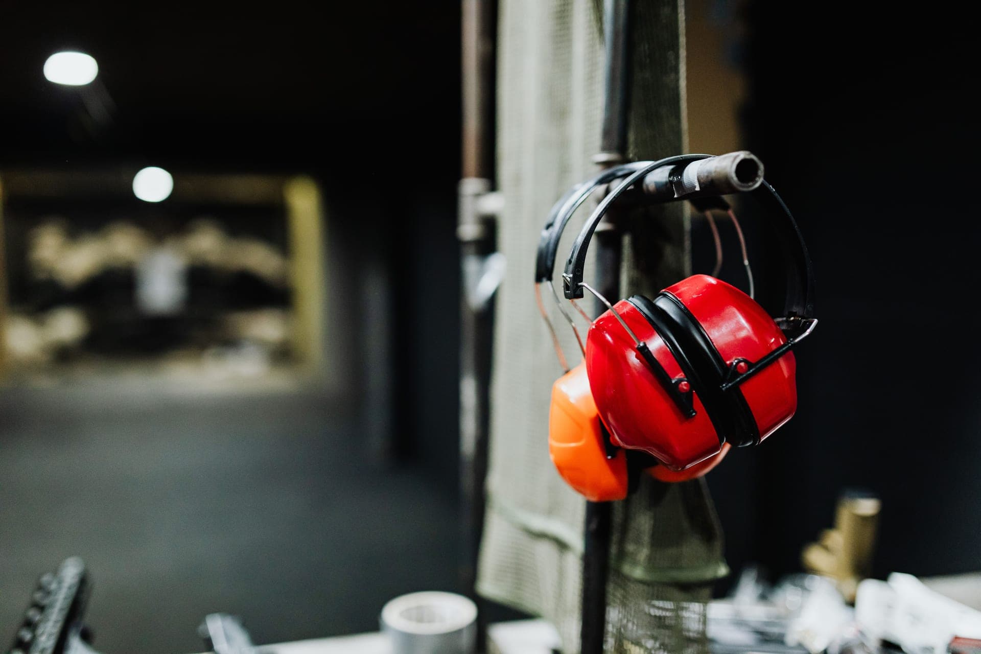 Red ear muffs hanging at an indoor shooting range