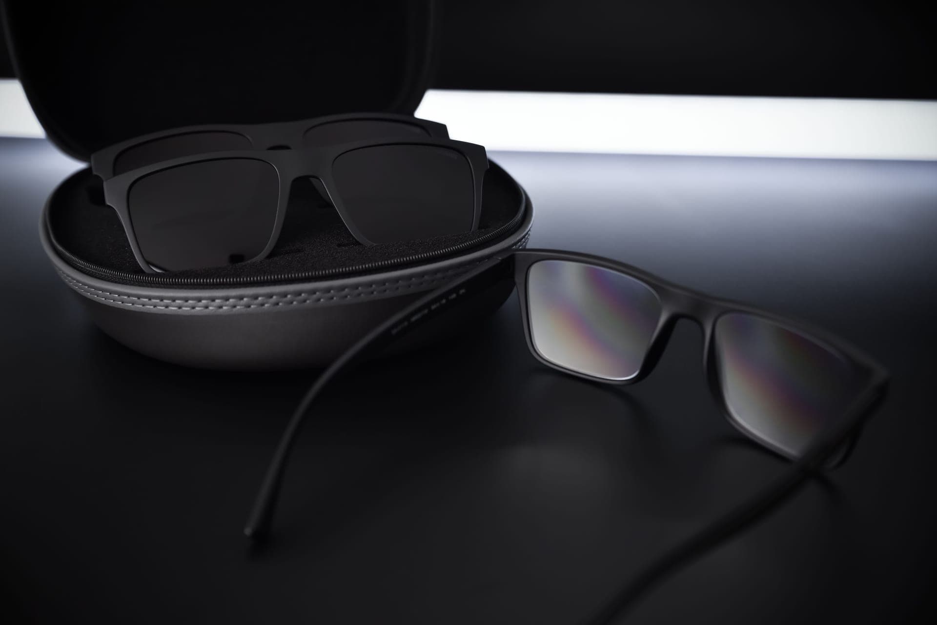 Illustrative stock photo: black sunglasses and a case on a reflective surface