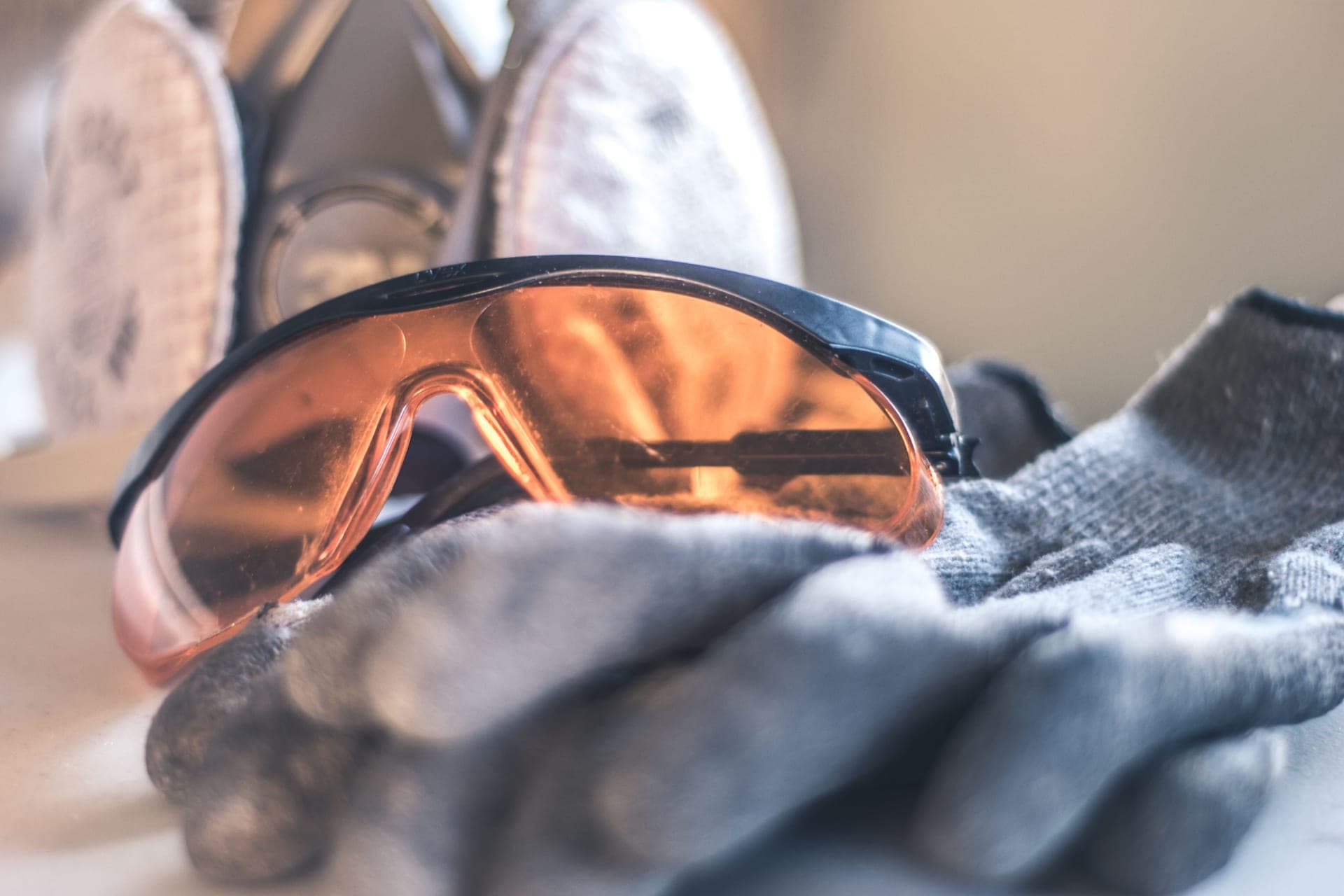 Clear safety glasses beside work gloves and a respirator on a bench