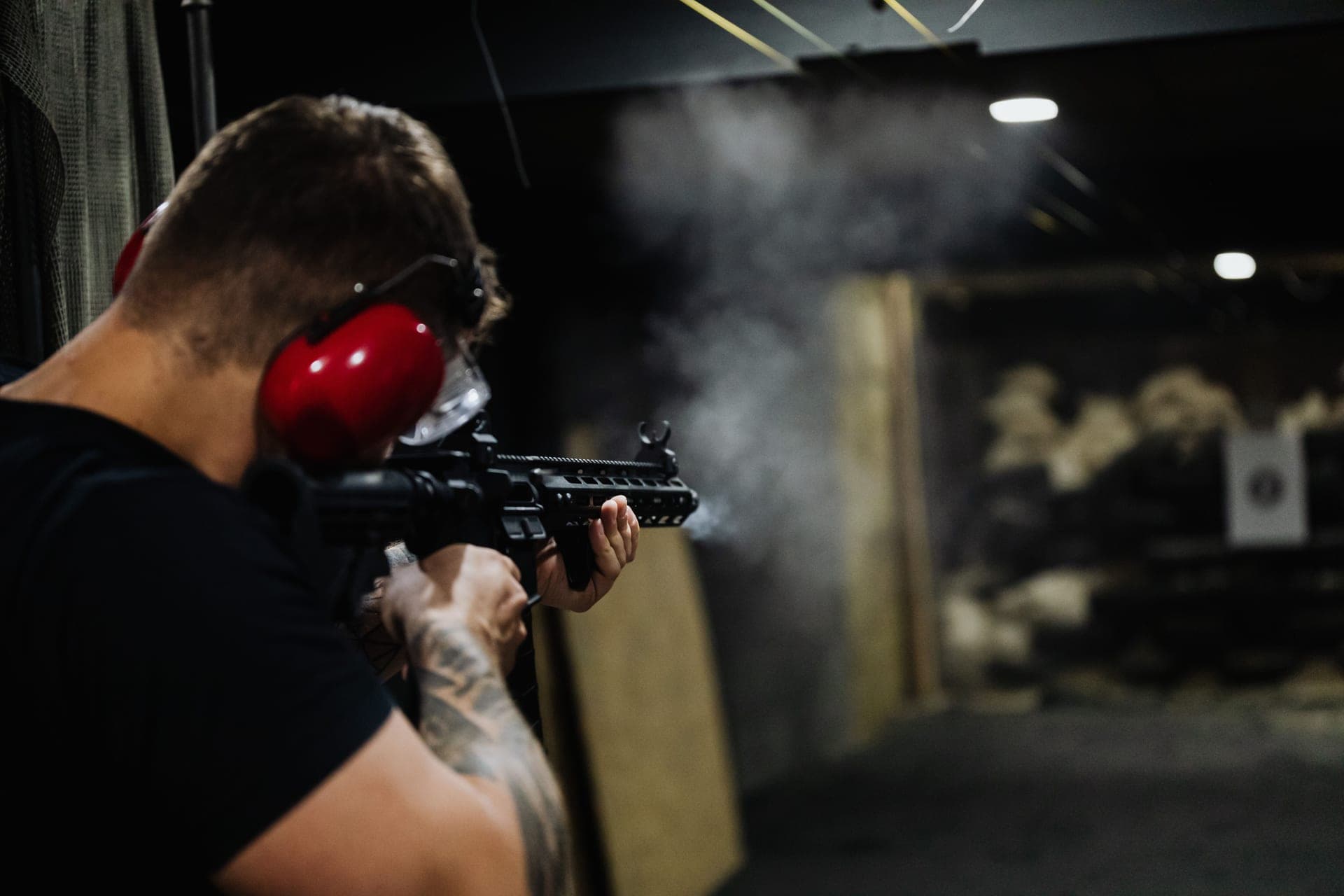 A man aiming a rifle on an indoor shooting range